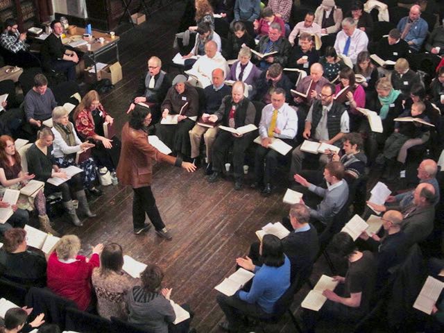 shape note singers sit facing each other across the usual hollow square